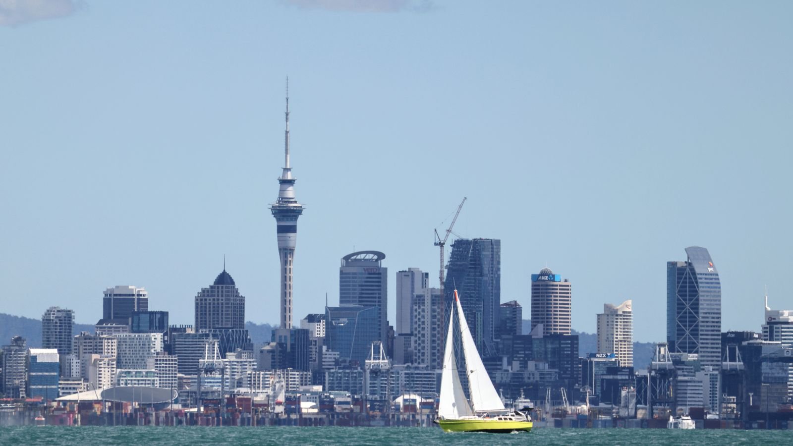 Sailboat on the Waitematā Harbour with the Auckland skyline and Sky Tower behind it