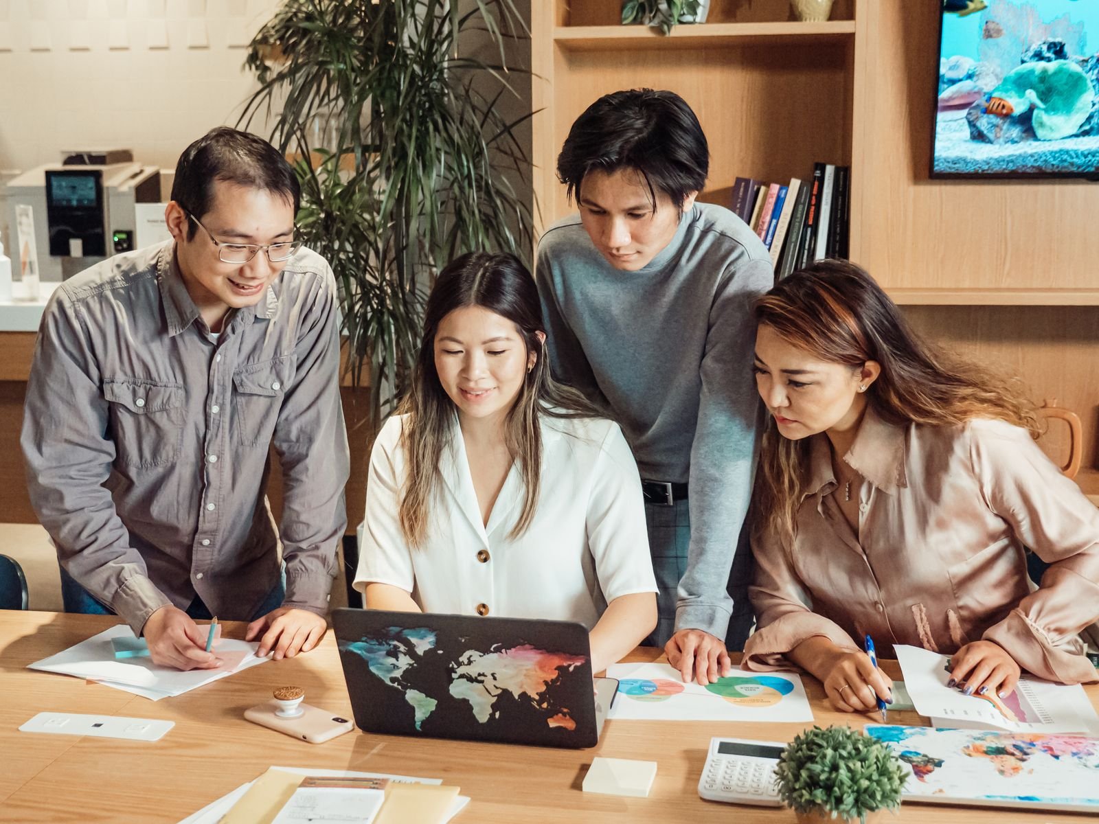 Colleagues gathered around a laptop planning content in an office